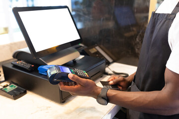 African american male barista using costumers creditar card for payment in a cafe