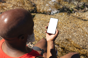 Senior african american man using smartphone by the sea