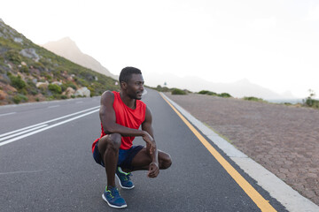 Fit african american man in sportswear stretching on a coastal road