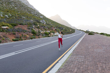 Fit african american woman in sportswear running on a coastal road