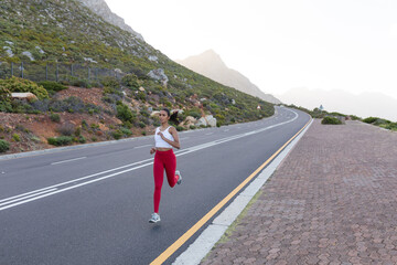 Fit african american woman in sportswear running on a coastal road