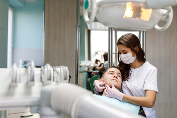 Portrait of young female dentist standing by mid adult man in clinic. Female dentist repairing...