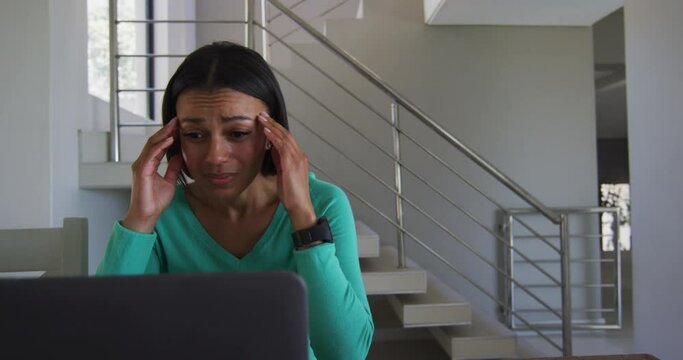 Stressed african american woman using laptop while working from home