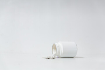 A pot of vitamins fallen over with vitamins spilling out