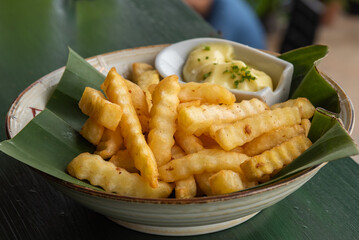French fries on banana leaf and ceramic bowl with mayo sauce.