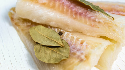 Sprinkle raw pollock fillet with salt, pepper and bay leaf.