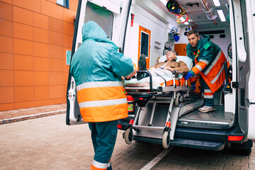 Confident and professional doctors unloading an ill patient from an ambulance car on a stretcher...