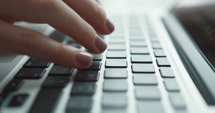 Close up of camera moving behind female hands typing text on laptop keyboard. Digital life. Online journalistic work.