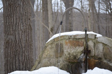Cool refreshing spring water running continuously from a manmade spout in the winter