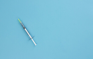 Naklejka premium Syringe for injection on a blue background. Top view. Healthcare concept. Vaccination. Copy space