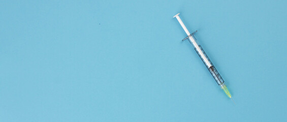 Naklejka premium Syringe for injection on a blue background. Top view. Healthcare concept. Vaccination. Copy space. Banner