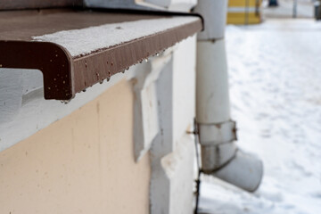 The facade of the building and window sills are covered with ice and snow. Severe frosts and a lot of snow in the city after a snowstorm and blizzard. danger of icicles falling from roofs.