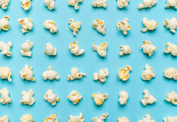 Popcorn flakes aligned on a blue background. Popcorn pattern, top view.