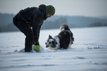 Men with border collie dog in winter landscape
