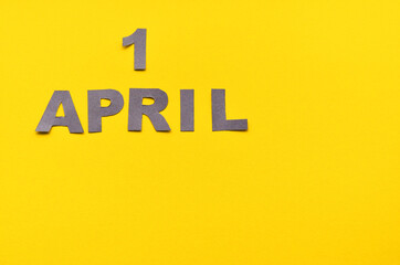 Inscription April 1 from carved letters of gray on a yellow background with copy space. High quality photo