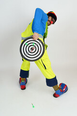 The clown holds a dartboard in his hands, covering her ass. Isolated on white
