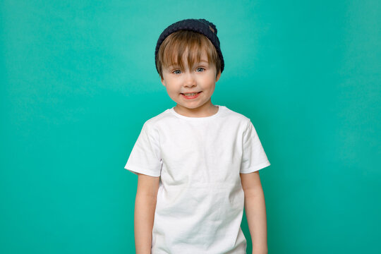 cute boy of five or six years old in a hat and a white T-shirt poses for the camera with a cute smile. Portrait
