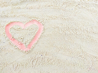 Pink heart contour painted on sandy beach