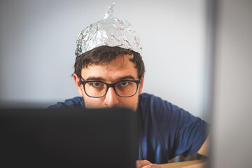 Conspiracy theory concept: young man is wearing aluminum head - obrazy, fototapety, plakaty