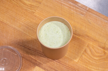closeup of cream soup in kraft paper food container for delivery
