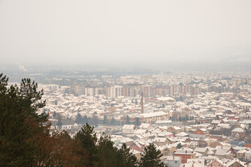 Pirot city panorama covered by snow on a cold, winter day with a gray sky and hazy atmosphere