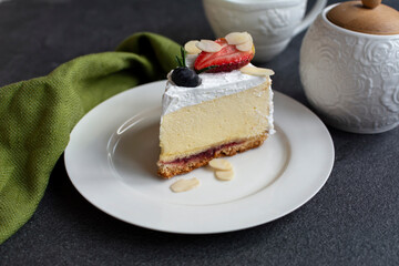 Cheesecake decorated with berries and almond flakes. A light and creamy dessert on white plate