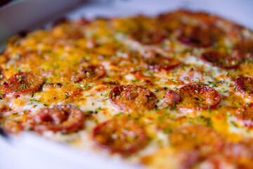 pizza recién horneada con queso, pepperoni y orégano por encima en una caja lista para entregar