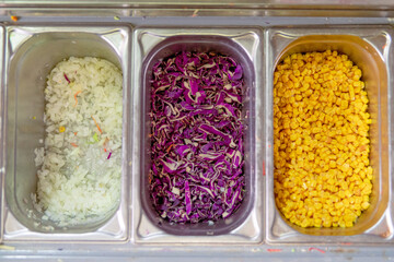 tres recipientes con ingredientes preparados para añadir a la comida, uno con lechuga, otro con...