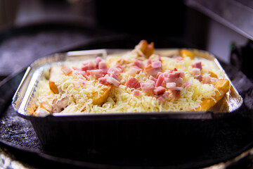bandeja de patatas fritas con queso y jamón lista para hornear