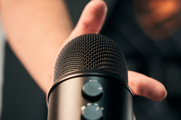 close up view of a male hand about to take a black microphone