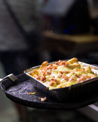 bandeja de patatas con queso fundido y jamón recién salida del horno