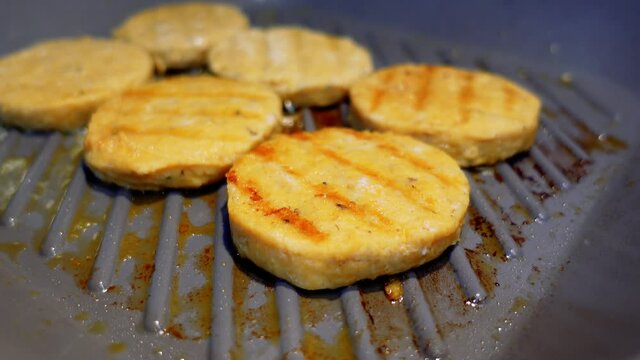 Cutlet in a grill pan. Fish burger cutlet frying in oil on hot pan. Cooking process in close up.