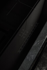 Black induction cooker for cooking in the kitchen, close-up. Touch-sensitive kitchen panel. Modern kitchen detail.