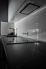 modern white kitchen with black countertop and induction touch plate. In the dim light