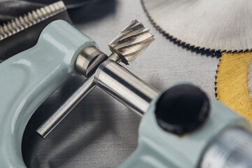 Measuring with micrometer end mill for locksmithing work on steel plate. Locksmithing workshop.