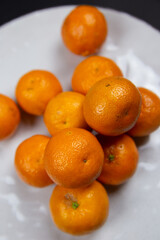 Large textured plate with tangerines, on a black background.