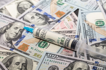 Syringe with 100 dollar banknote inside on dollar banknotes