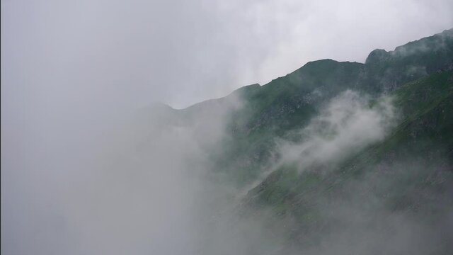 Fagaras mountains covered in clouds. Clouds moving fast and revealing the peaks of the mountain. Fagaras are a mountain group of  Carpathians