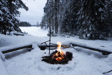 Bright bonfire in a winter forest. Beautiful snow covered trees. Kettle on fire. Camping, hiking...