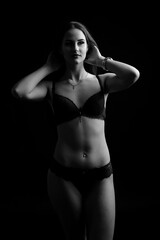 Portrait of brunette girl in underwear standing in the studio with black background.