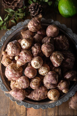 Jerusalem artichokes or topinambour, (topinambur), also known as earth apple or sunroot on wooden background.