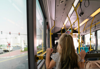 Obraz premium light-haired girl riding a bus, view from the back