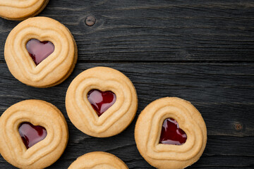 Cookies. Cookie Hearts shape Red jam or strawberry jelly inside biscuit cookie. Homemade baking. Sweet bakery. Top view on black background with copy space.
