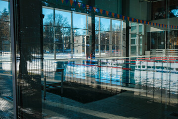 Fototapeta na wymiar Indoor empty swimming pool in blur background. Reflection of snow in the water. Sunny winter day. Lockdown.