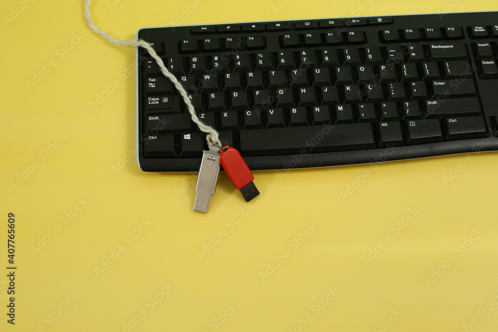 Poster top view of a computer keyboard and usb flash drives on it displayed on a yellow background