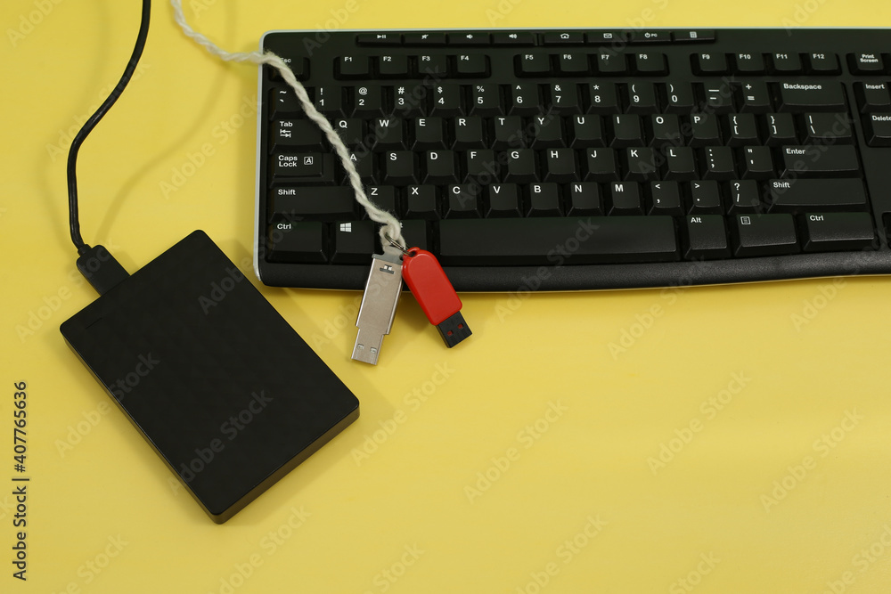 Poster computer keyboard, external hard drive, and usb flash drive displayed on a yellow background