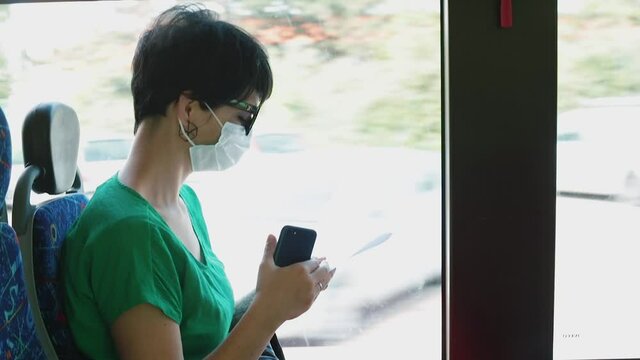 Respiratory protection from an allergic reaction in a public place. A woman in a mask on her face rides a bus. 