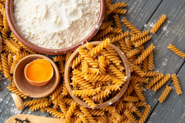wholemeal raw pasta fusilli type, flour and egg, garlic on an old table