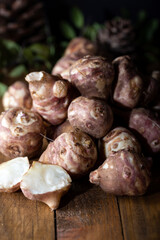 Jerusalem artichokes or topinambour, (topinambur), also known as earth apple or sunroot on wooden background. Close up.