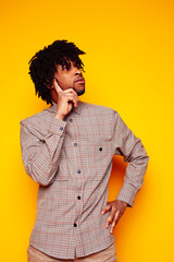 young handsome african american guy student posing cheerful and gesturing on yellow background, lifestyle people concept